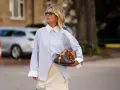 Mujer con camisa oversize azul, falda lencera de encaje y bolso de diseño. Un look para tunear ropa de mujer con estilo.