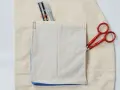 Detalles de costura y herramientas para crear diferentes tipos de bolsillos para abrigos. Tijeras rojas y un rotulador de tela.