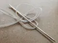 Aguja con hilo blanco enredado, lista para coser a punto de lado.