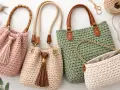 Bolsos de ganchillo con borlas y asas de cuero. Un bolso verde grande y uno blanco pequeño con cadena dorada. La costura provisional a punto largo es visible en todos.