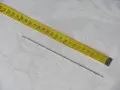 Una aguja de coser plateada y una cinta métrica amarilla, que muestra medidas en centímetros. La aguja, que es como un punzón fino, está lista para usarse.