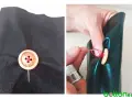 Demostración de cómo coser un botón de madera a tela negra con hilo rojo. Se ve el botón ya fijado y luego el proceso de coserlo.