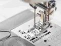 Primer plano del prensatelas de una máquina de coser, listo para guiar la tela con precisión.