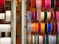 Variedad de tipos de cintas de tela en rollos, con colores y texturas diversas, ideales para manualidades y decoración.