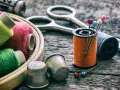 Herramientas para arreglar una ropa con un trozo del mismo tipo: hilos de colores, tijeras, dedales y alfileres.