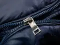 Enganche cremallera roto en chaqueta azul marino. El tirador metálico está desprendido, dejando la cremallera inutilizable.