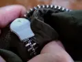 Mano arreglando cremallera doble carro de chaqueta verde.