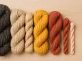 Ovillos de lana de diferentes grosores y colores: gris oscuro, beige, amarillo mostaza, terracota y rosa pálido. El hilo parece ser de lana, de que esta hecho el hilo.