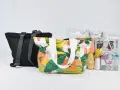 Bolsas de tela con estampado floral y una bolsa transparente con materiales de costura, incluyendo un patrón.