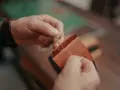 Manos cosiendo a mano un monedero de cuero. Se aprecian los detalles de los tipos de costuras de cuero a mano.