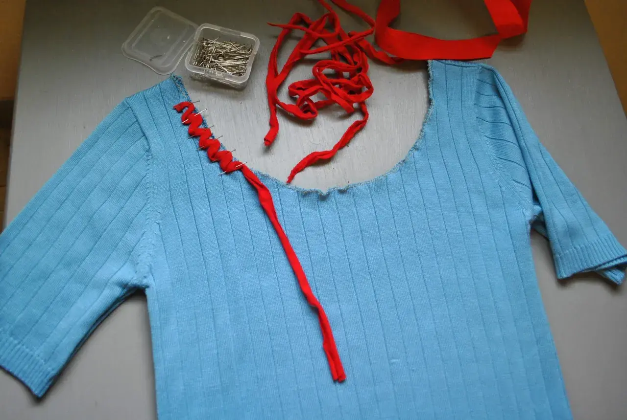 Jersey azul de punto con cuello cortado y tijeras.