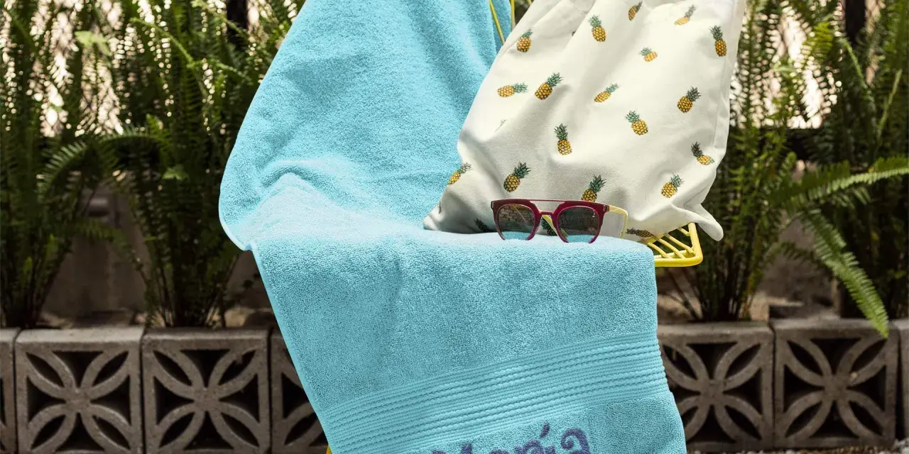 Toalla turquesa con el nombre "María" bordado, lista para la playa.