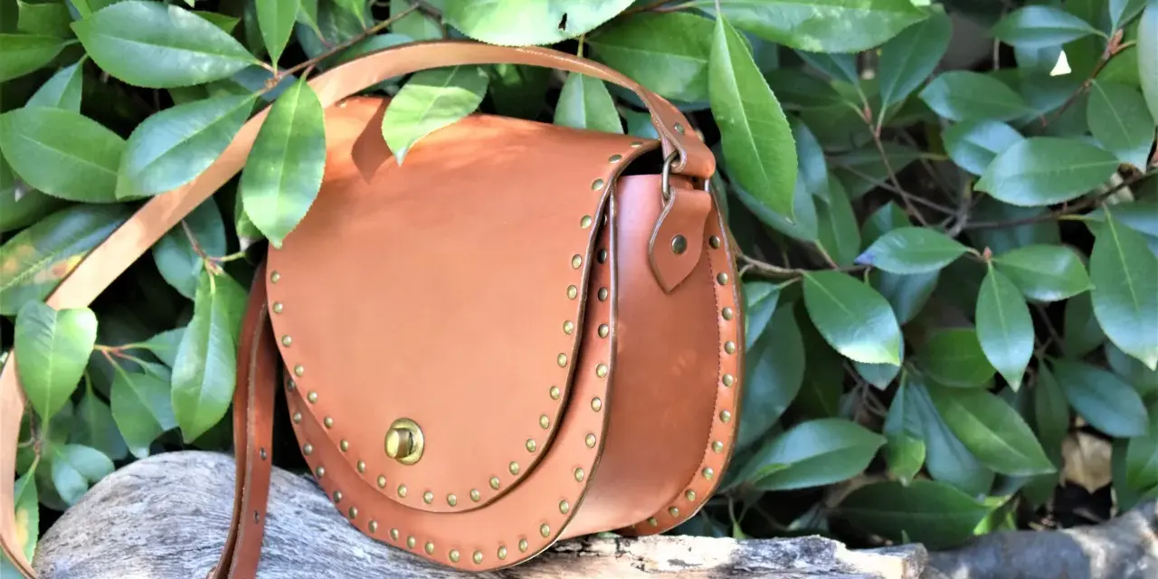 Bolso de cuero marrón con tachuelas, ideal para quienes buscan patrones de bolsos gratis para descargar y crear sus propios accesorios.