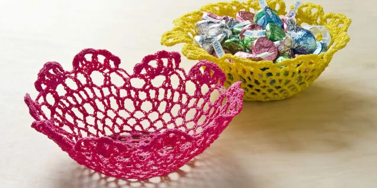 Dos cuencos de ganchillo, uno rosa y otro amarillo lleno de caramelos. Aprende como dar rigidez a una tela para crear estas piezas decorativas.
