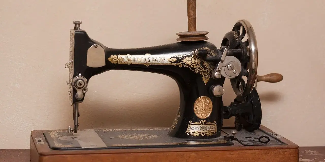 Máquina de coser Singer antigua, pieza clave en la historia de la costura, con detalles dorados y base de madera.