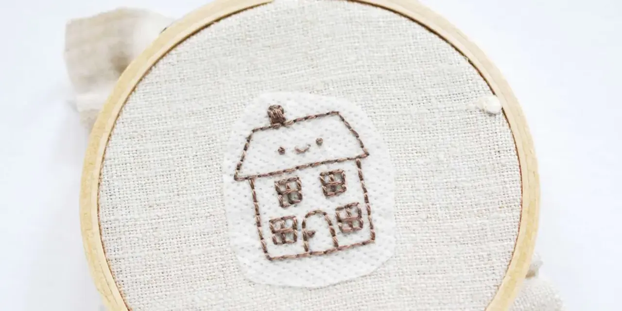 Bordado de una casita sonriente sobre papel para bordar que se deshace con el agua.