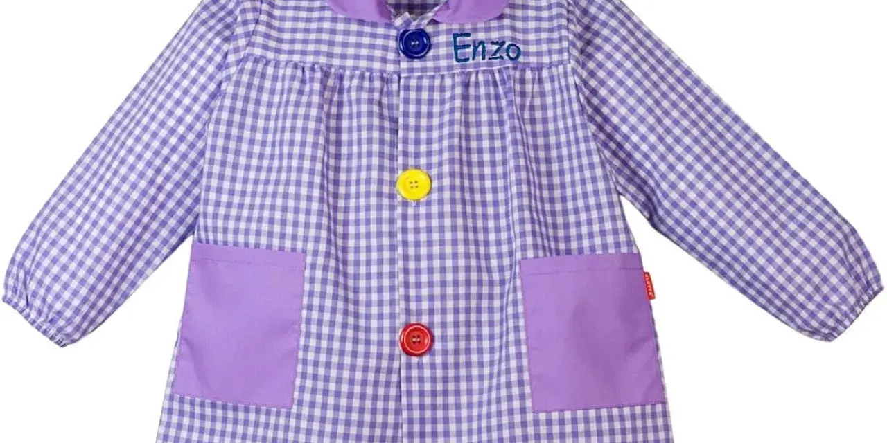 Batas con nombre bordado "Enzo", a cuadros lilas y blancos, con bolsillos y botones de colores.