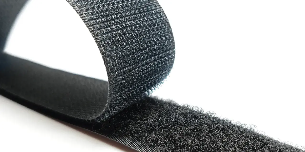 Cinta negra con dos caras: una suave y otra con pequeños ganchos. Así es que es velcro, ideal para unir objetos.