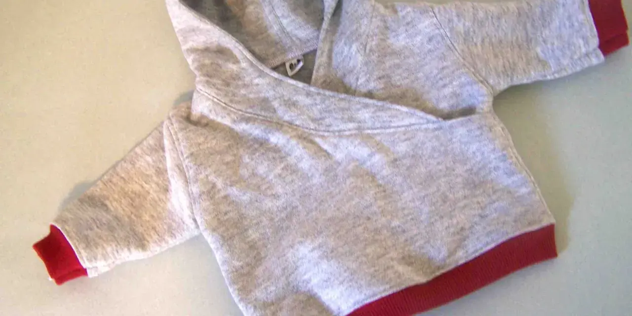 Saco de bebé gris con capucha y puños rojos. Un patrón de saco de bebé con capucha listo para coser.