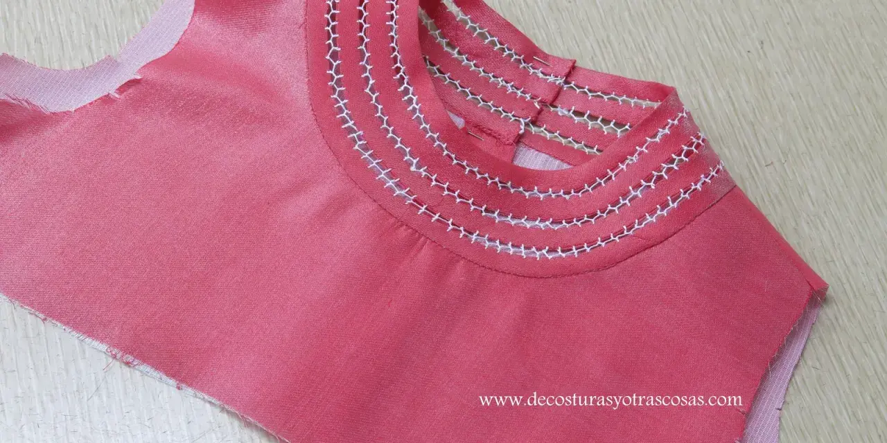 Detalle de camiseta rosa con bordado a mano en el cuello, creando un diseño delicado y único.