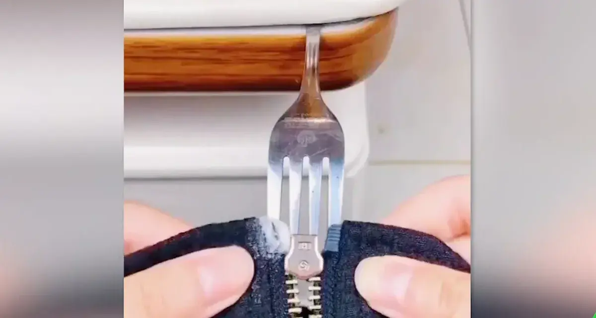 Demostración de como arreglar una cremallera con un tenedor. Un tenedor se usa para manipular una cremallera atascada.