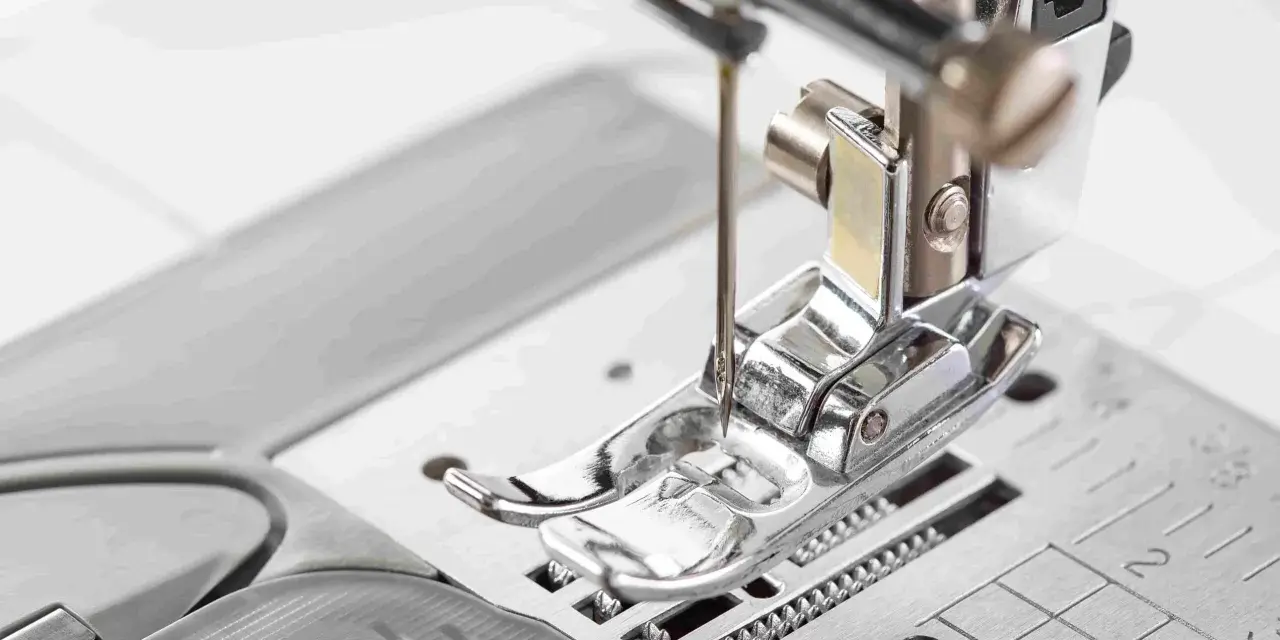 Primer plano del prensatelas de una máquina de coser, listo para guiar la tela con precisión.