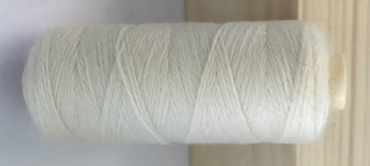 Rollo de hilo blanco de merino lana, listo para tejer prendas suaves y cálidas.