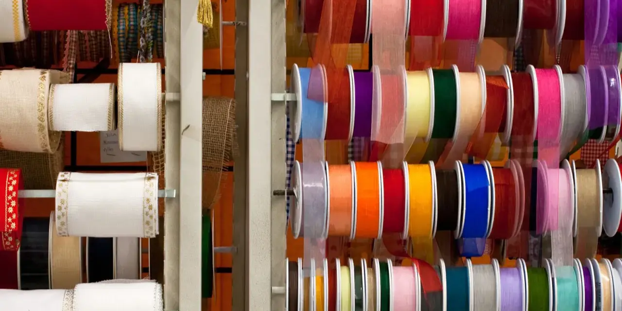 Variedad de tipos de cintas de tela en rollos, con colores y texturas diversas, ideales para manualidades y decoración.