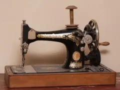 Máquina de coser Singer antigua, pieza clave en la historia de la costura, con detalles dorados y base de madera.