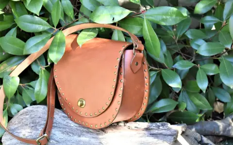 Bolso de cuero marrón con tachuelas, ideal para quienes buscan patrones de bolsos gratis para descargar y crear sus propios accesorios.
