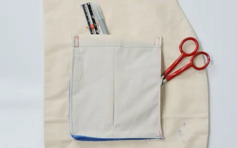 Detalles de costura y herramientas para crear diferentes tipos de bolsillos para abrigos. Tijeras rojas y un rotulador de tela.