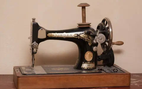 Máquina de coser Singer antigua, pieza clave en la historia de la costura, con detalles dorados y base de madera.