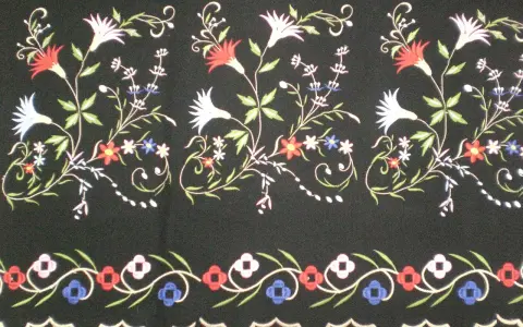 Delicados dibujos para refajos bordados con flores y hojas en tonos rojos, blancos, azules y verdes sobre fondo negro.