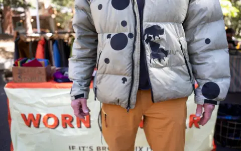 Hombre con chaqueta acolchada beige con manchas negras y bisontes. Aprende como arreglar una chaqueta acolchada para que dure.