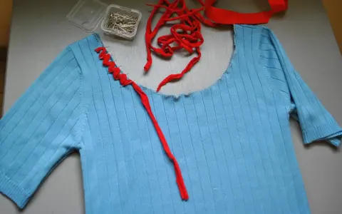 Jersey azul de punto con cuello cortado y tijeras.