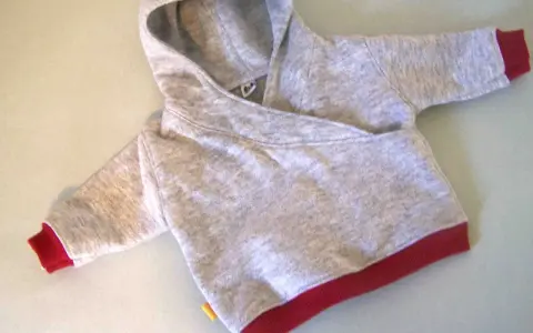 Saco de bebé gris con capucha y puños rojos. Un patrón de saco de bebé con capucha listo para coser.