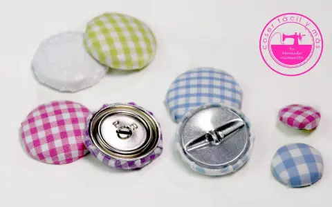 Botones forrados con tela de cuadros vichy en rosa, morado, verde y azul. Se ven los cierres metálicos.