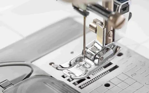 Primer plano del prensatelas de una máquina de coser, listo para guiar la tela con precisión.