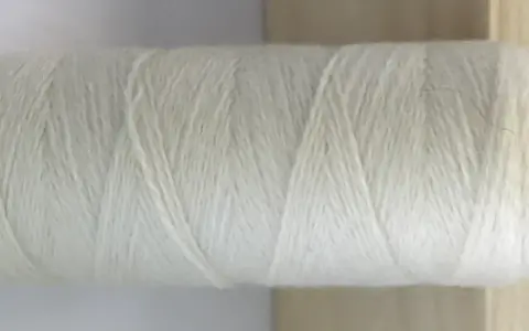Rollo de hilo blanco de merino lana, listo para tejer prendas suaves y cálidas.