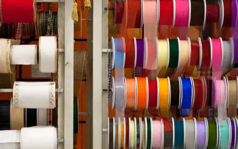 Variedad de tipos de cintas de tela en rollos, con colores y texturas diversas, ideales para manualidades y decoración.
