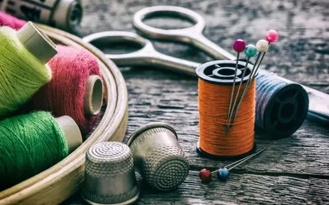 Herramientas para arreglar una ropa con un trozo del mismo tipo: hilos de colores, tijeras, dedales y alfileres.