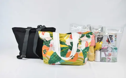 Bolsas de tela con estampado floral y una bolsa transparente con materiales de costura, incluyendo un patrón.