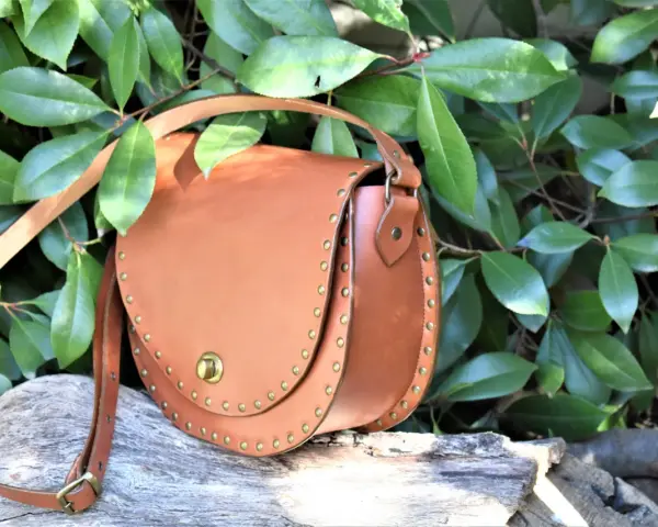 Bolso de cuero marrón con tachuelas, ideal para quienes buscan patrones de bolsos gratis para descargar y crear sus propios accesorios.