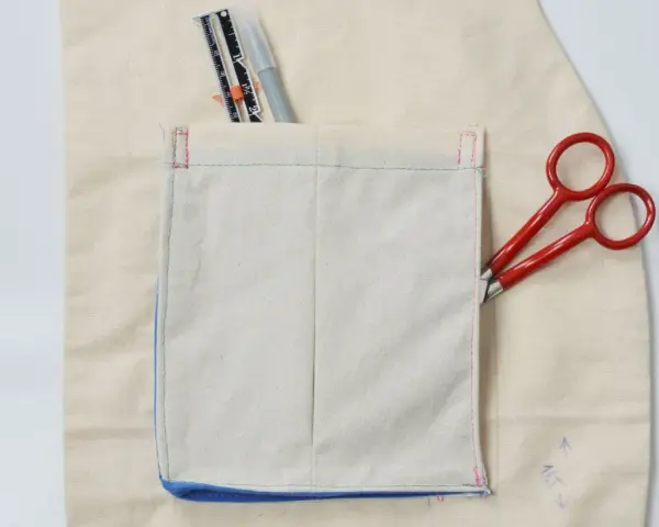 Detalles de costura y herramientas para crear diferentes tipos de bolsillos para abrigos. Tijeras rojas y un rotulador de tela.