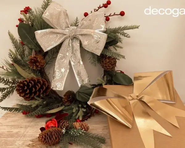 Corona navideña con lazo plateado y regalos con lazo dorado. Aprende como hacer un lazo con cinta ancha para tus decoraciones.