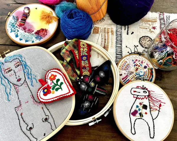 Un conjunto de aros de bordado con diseños coloridos y un estilo de bordado creativo. Hay un retrato de mujer, un corazón, un caballo y otros motivos.