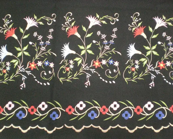 Delicados dibujos para refajos bordados con flores y hojas en tonos rojos, blancos, azules y verdes sobre fondo negro.