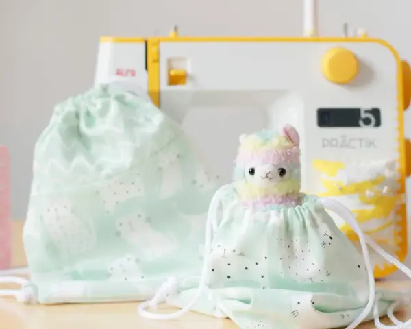 Un patrón de mochila de tela con un adorable diseño de gatitos y un peluche de llama arcoíris, listo para ser cosido.