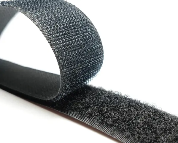 Cinta negra con dos caras: una suave y otra con pequeños ganchos. Así es que es velcro, ideal para unir objetos.