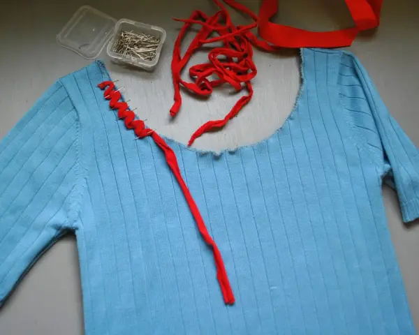 Jersey azul de punto con cuello cortado y tijeras.